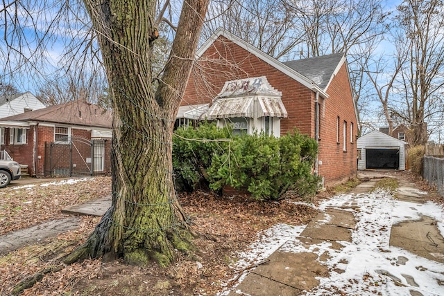 view of snowy exterior featuring an outbuilding and a garage