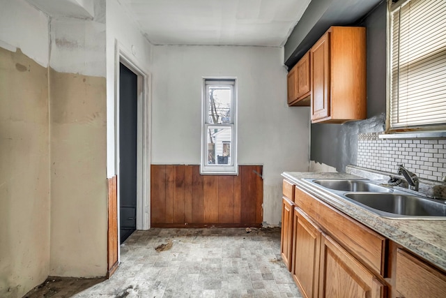 kitchen with backsplash, wood walls, and sink