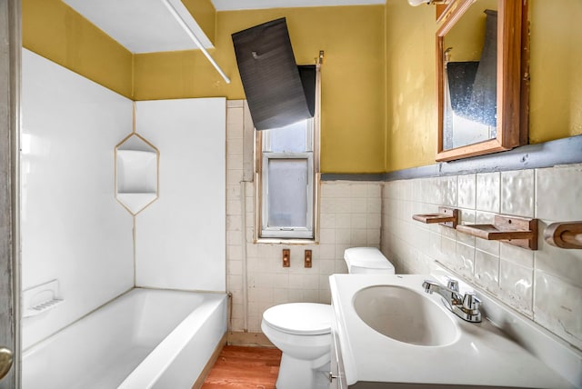 bathroom featuring vanity, a bath, hardwood / wood-style flooring, toilet, and tile walls