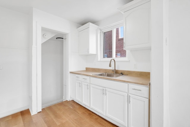 kitchen featuring light hardwood / wood-style floors, white cabinetry, and sink