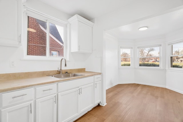 kitchen with white cabinets, light hardwood / wood-style flooring, and sink