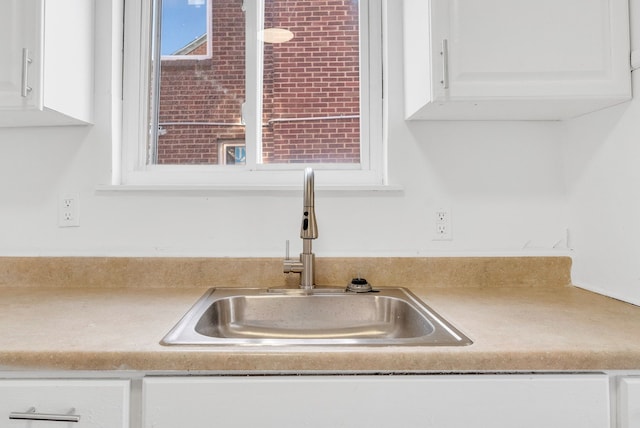 interior details featuring white cabinets and sink