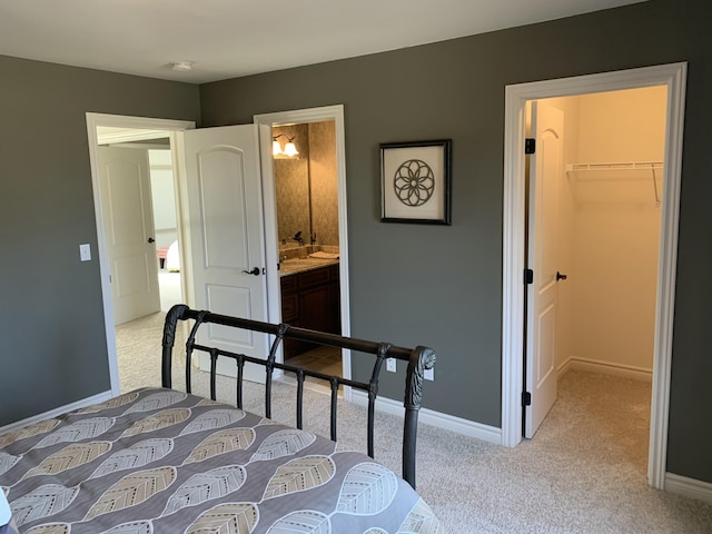 bedroom with a spacious closet, a closet, ensuite bathroom, and light carpet