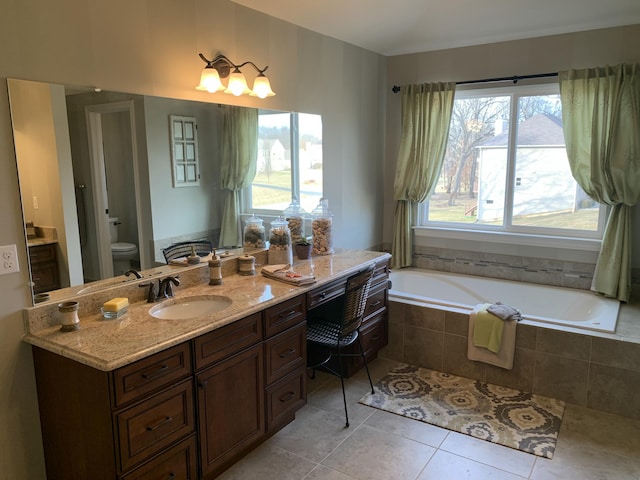 bathroom with tiled tub, tile patterned flooring, vanity, and toilet