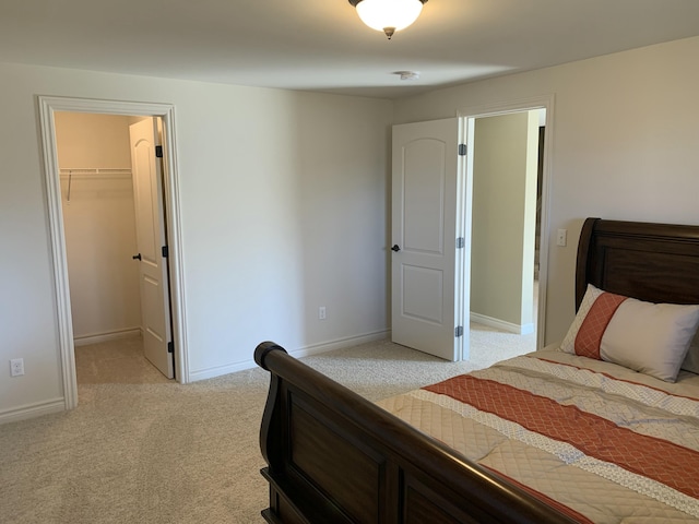 bedroom featuring a walk in closet, light carpet, and a closet