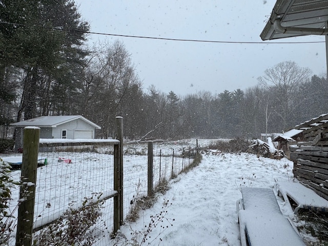 yard layered in snow with a garage and an outdoor structure