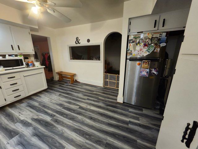 kitchen featuring white cabinets, stainless steel fridge, ceiling fan, and dark wood-type flooring