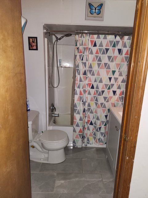 full bathroom with shower / tub combo, vanity, toilet, and tile patterned floors