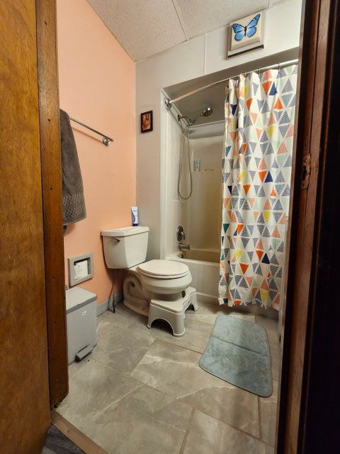 bathroom with toilet and shower / bathtub combination with curtain