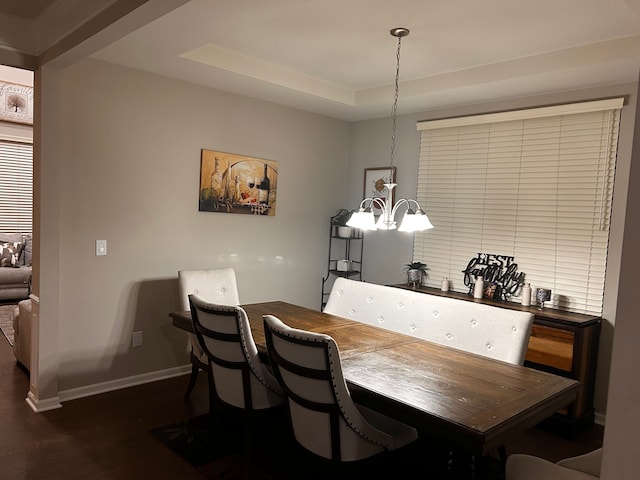 dining space featuring dark hardwood / wood-style floors, a raised ceiling, and a notable chandelier