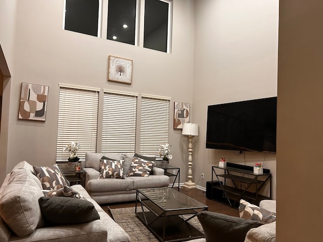 living room with hardwood / wood-style floors and a towering ceiling