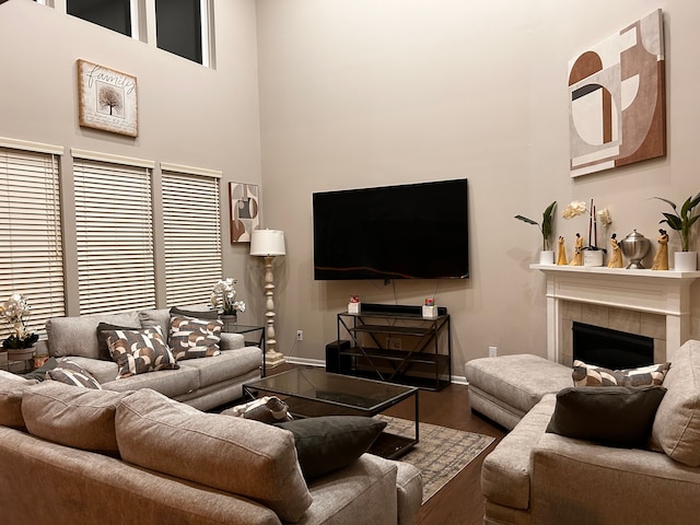 living room featuring a fireplace, wood-type flooring, and a high ceiling