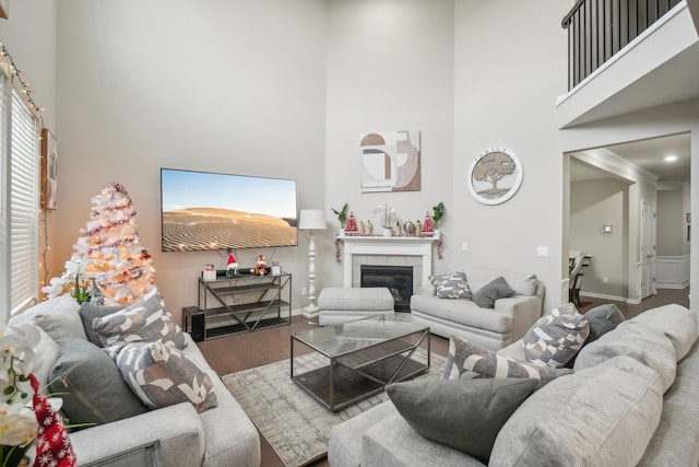 living room with a towering ceiling, hardwood / wood-style flooring, and a tiled fireplace