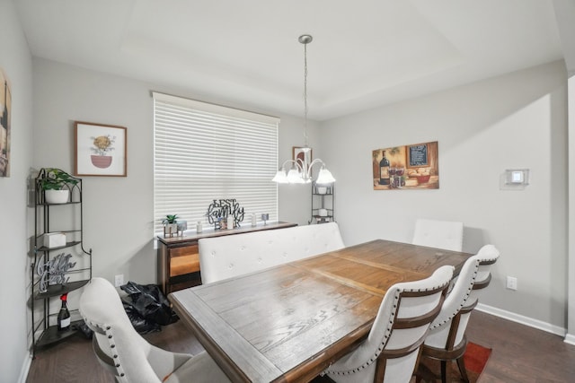 dining area with a tray ceiling, a chandelier, and dark hardwood / wood-style floors