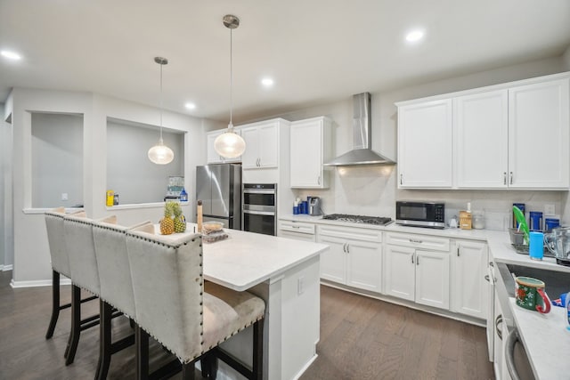 2785 Tulip Way, Commerce Twp, MI 48382 - kitchen featuring appliances with stainless steel finishes, wall chimney range hood, a kitchen island, dark wood finished floors, and white cabinets