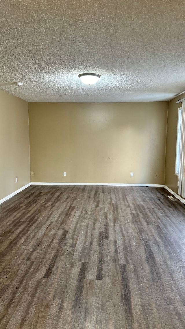 empty room with dark hardwood / wood-style floors and a textured ceiling