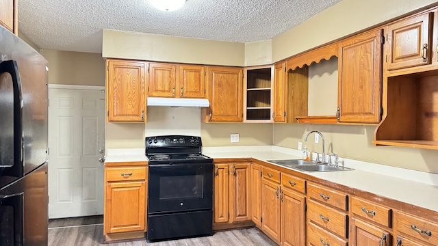 kitchen with black electric range oven, sink, a textured ceiling, light wood-type flooring, and stainless steel fridge