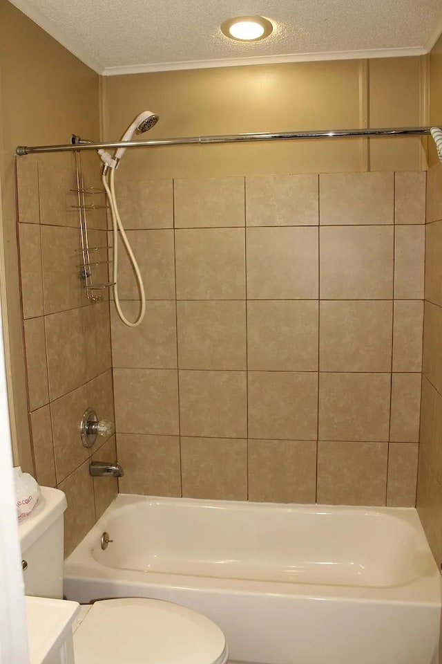 bathroom featuring tiled shower / bath, toilet, and a textured ceiling