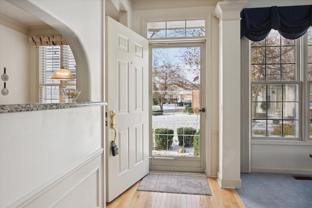 entryway featuring crown molding, plenty of natural light, and light hardwood / wood-style floors