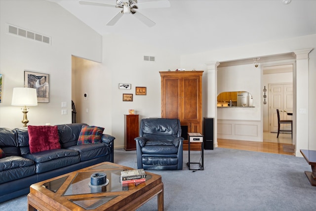 carpeted living room with ornate columns, ceiling fan, and lofted ceiling