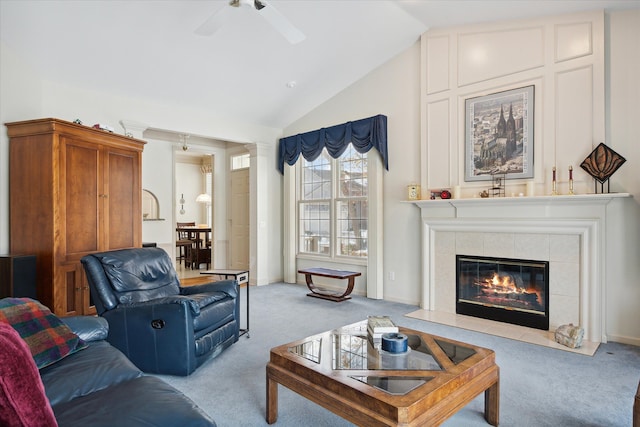 carpeted living room with a tiled fireplace, ceiling fan, and lofted ceiling