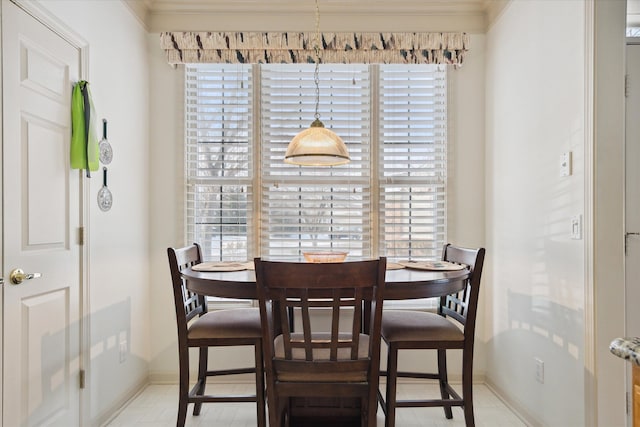 tiled dining space with a healthy amount of sunlight and ornamental molding