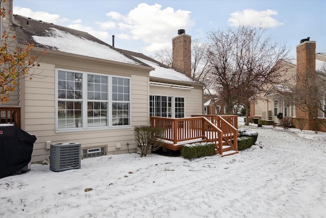 snow covered back of property featuring central AC unit and a deck