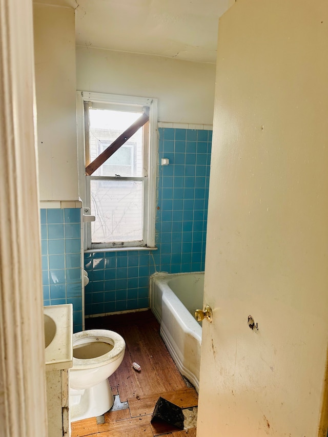 bathroom featuring hardwood / wood-style flooring, toilet, and tile walls