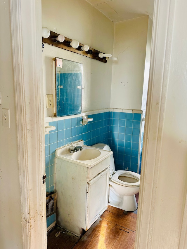 bathroom with hardwood / wood-style floors, vanity, tile walls, and toilet