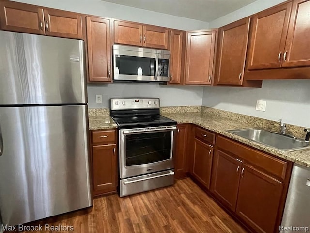 kitchen with light stone countertops, sink, dark hardwood / wood-style floors, and appliances with stainless steel finishes