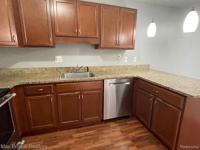 kitchen with kitchen peninsula, appliances with stainless steel finishes, sink, pendant lighting, and dark hardwood / wood-style floors