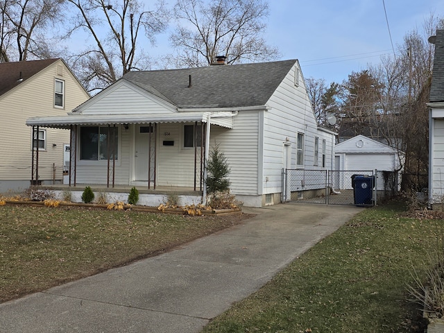 bungalow-style home featuring covered porch, a front yard, an outbuilding, and a garage