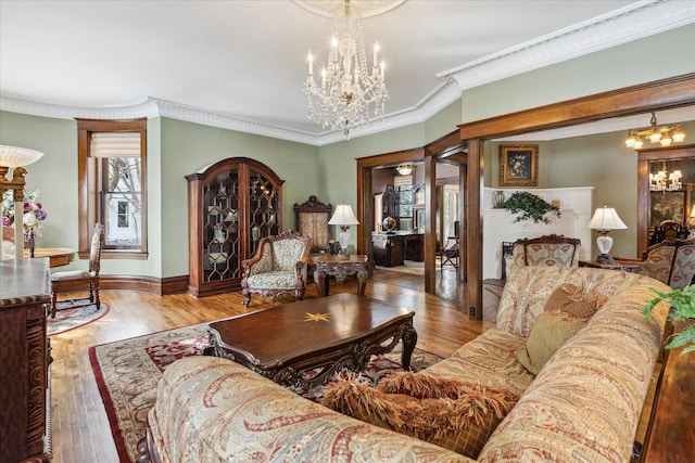 living room with a chandelier, ornamental molding, and light hardwood / wood-style flooring