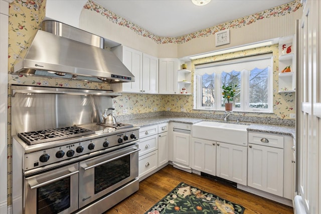 kitchen featuring white cabinetry, sink, wall chimney exhaust hood, and range with two ovens