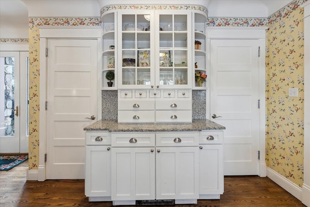 interior space with backsplash, light stone countertops, white cabinets, and dark hardwood / wood-style floors