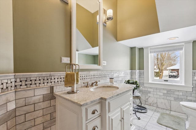 bathroom with vanity, toilet, and tile walls