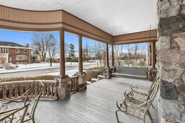 snow covered deck featuring covered porch