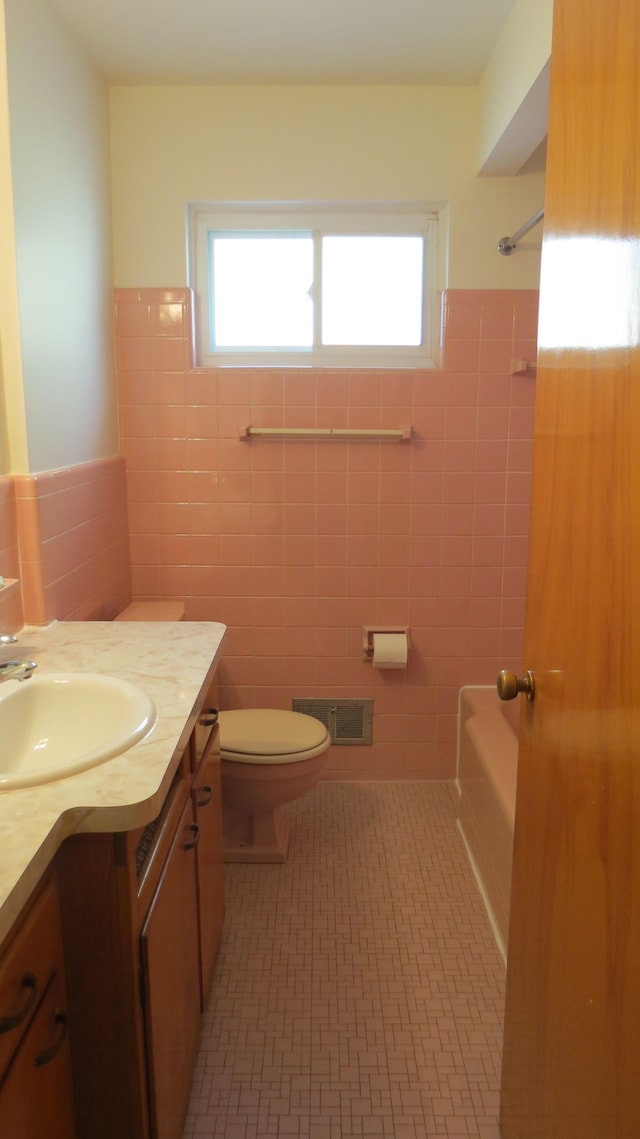 bathroom with tile patterned flooring, vanity, toilet, and tile walls