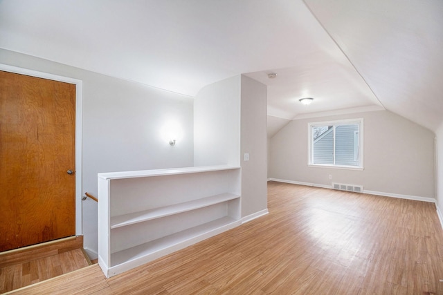 bonus room with light wood-type flooring and vaulted ceiling