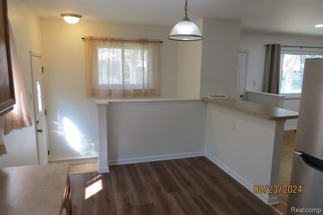 kitchen featuring kitchen peninsula, white fridge, decorative light fixtures, and dark hardwood / wood-style floors