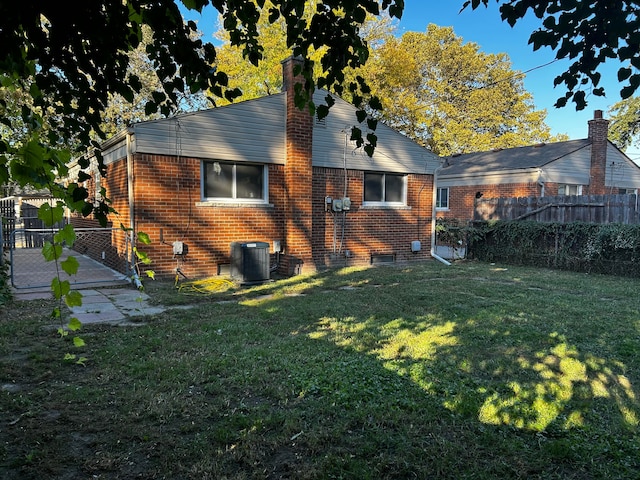 rear view of house featuring cooling unit and a lawn