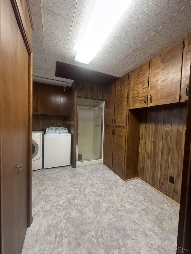 interior space featuring wood walls, cabinets, and washing machine and clothes dryer