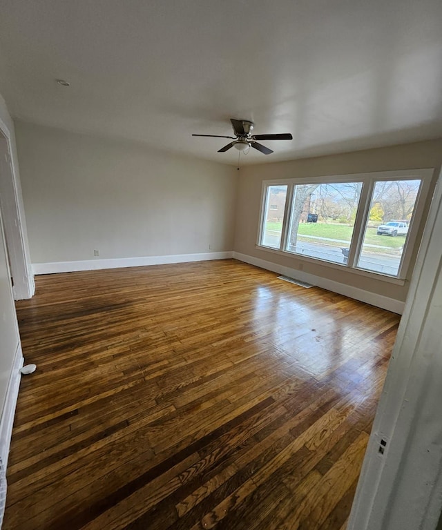 empty room with a wealth of natural light, ceiling fan, and dark hardwood / wood-style floors