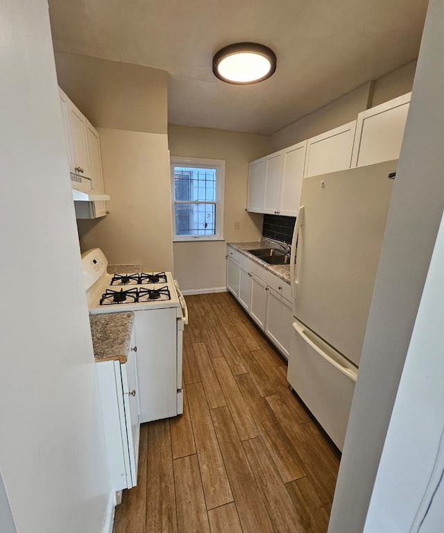 kitchen with white cabinetry, sink, backsplash, white appliances, and hardwood / wood-style flooring