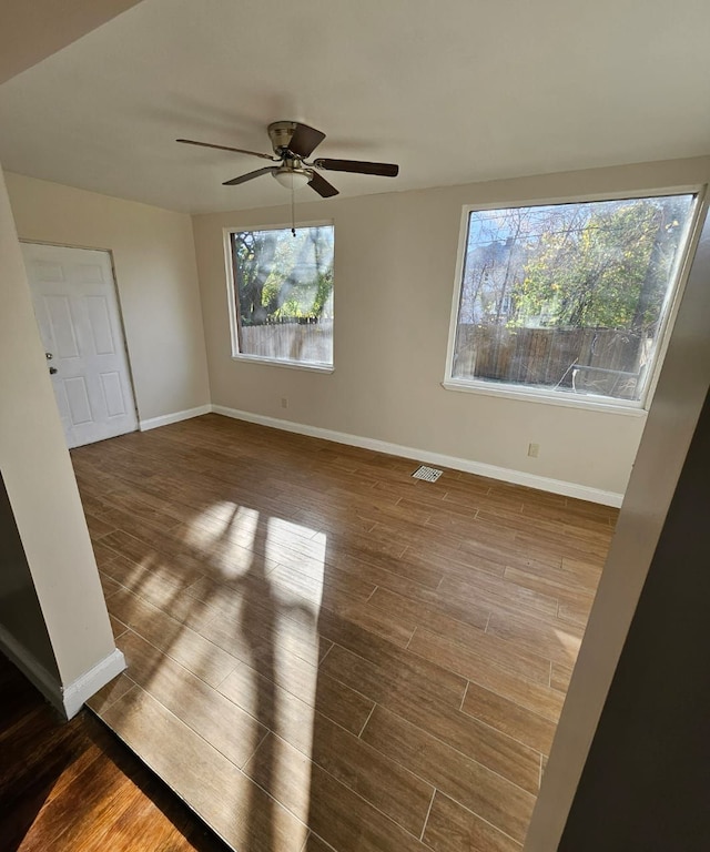 spare room featuring hardwood / wood-style floors, ceiling fan, and a healthy amount of sunlight