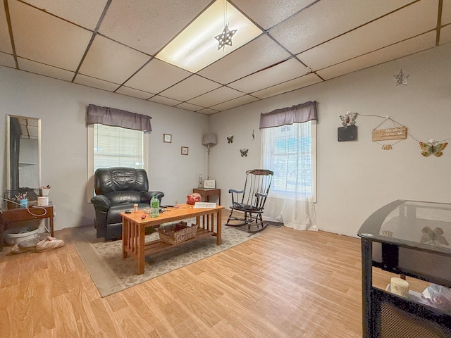 sitting room with a paneled ceiling, wood-type flooring, and a wealth of natural light