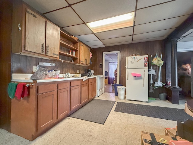 kitchen featuring a paneled ceiling, wood walls, white appliances, and sink