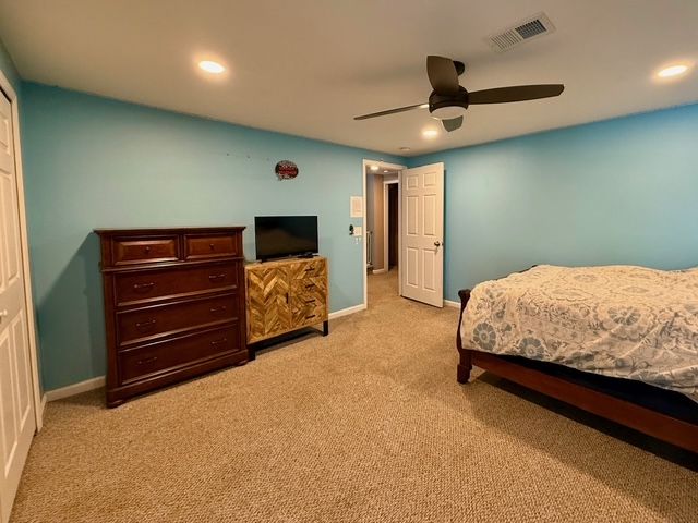 bedroom featuring ceiling fan, light colored carpet, and a closet