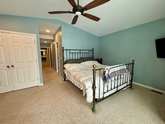 carpeted bedroom featuring a closet, ceiling fan, and lofted ceiling