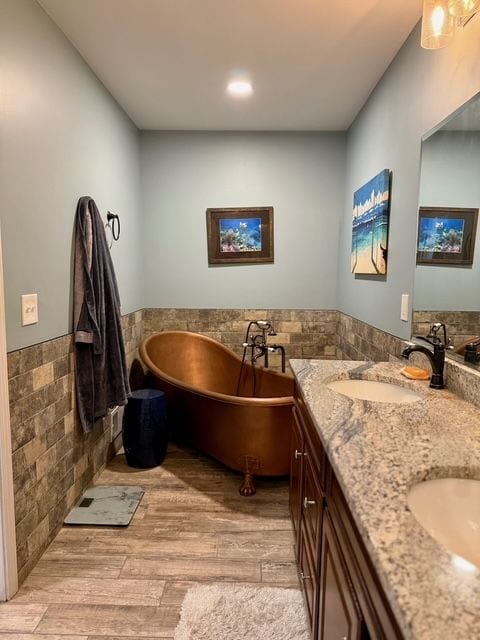 bathroom featuring hardwood / wood-style flooring, vanity, tile walls, and a tub